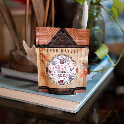 Barrel conditioned coffee bag with Thou Mayest Caffé Amaro branding on a shelf.