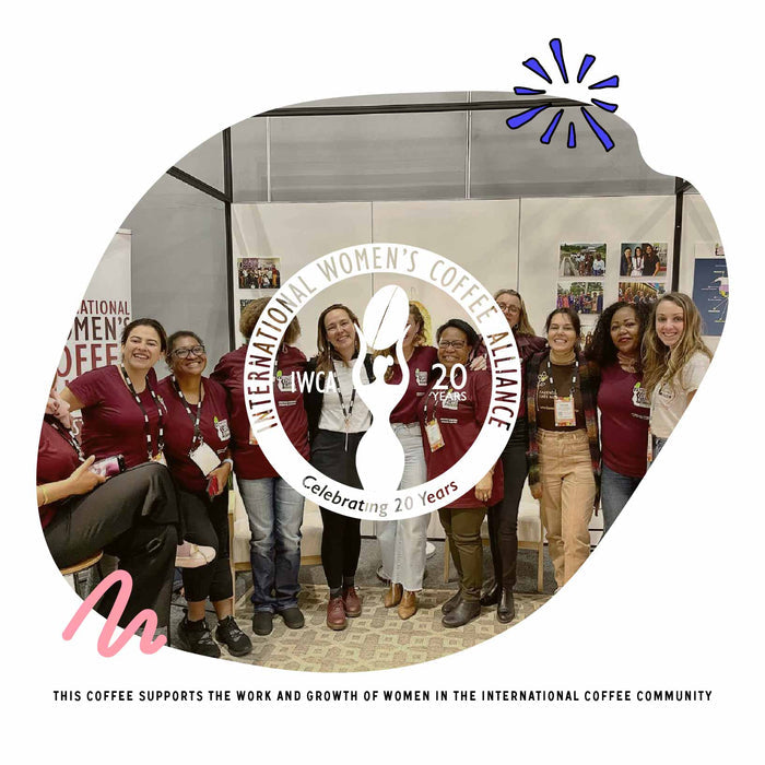 Group of women in maroon shirts posing at a coffee event with an International Women's Coffee Alliance logo overlay