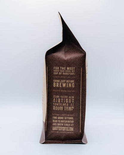 Decaf Colombia coffee bag with a folded top and brown label against a pale blue background