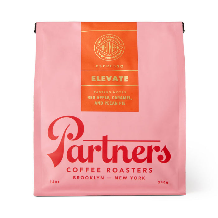 Pink Elevate coffee bag from Partners Coffee Roasters with an orange tasting notes panel listing red apple caramel and pecan pie.