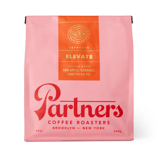 Pink Elevate coffee bag from Partners Coffee Roasters with an orange tasting notes panel listing red apple caramel and pecan pie.