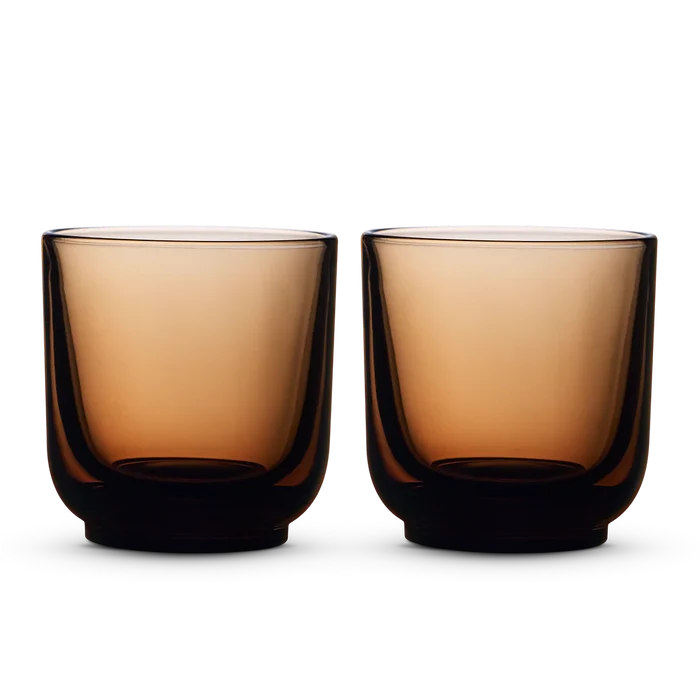 Two amber Fellow Pirch espresso shot glasses on a black background