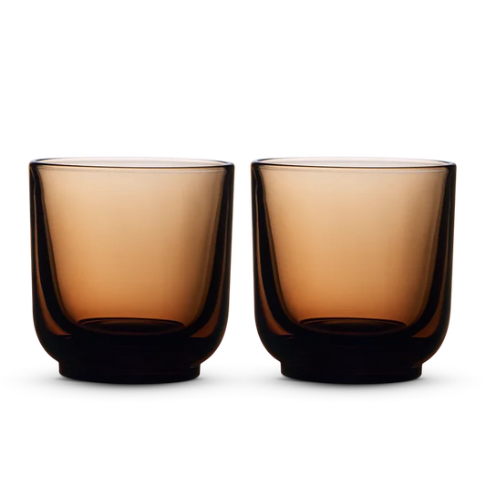 Two amber Fellow Pirch espresso shot glasses on a black background