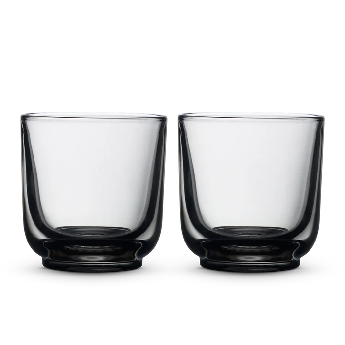 Two clear Fellow Pirch espresso shot glasses on a black background