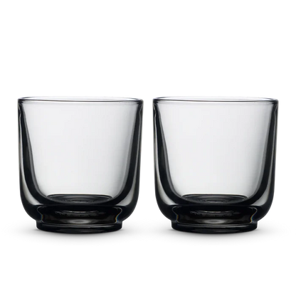 Two clear Fellow Pirch espresso shot glasses on a black background