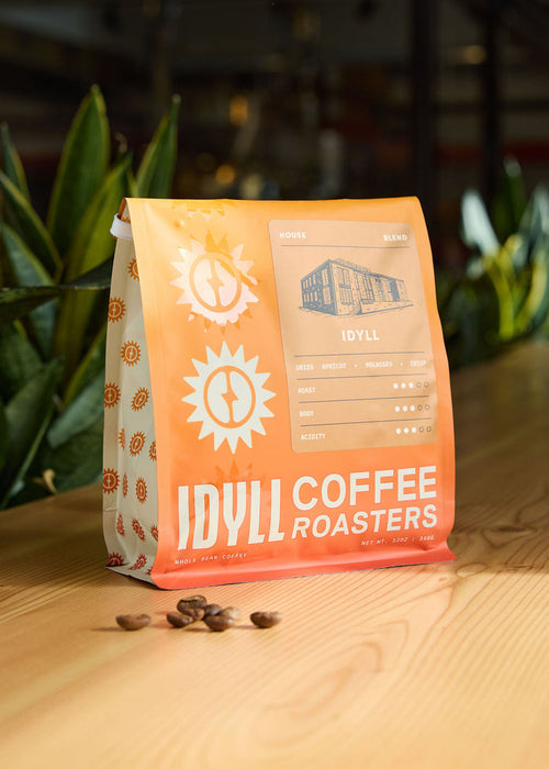 Idyll coffee bag from Idyll Coffee Roasters on a wooden table with roasted beans nearby