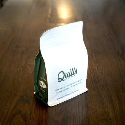 Inkwell coffee bag on a wooden table with a white mug of coffee in the foreground
