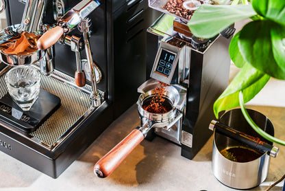 Lifestyle shot of LUCCA dosing funnel beside an espresso machine with a portafilter and ground coffee
