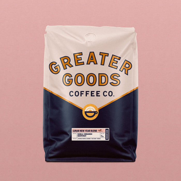 Lunar New Year Blend coffee bag by Greater Goods Coffee Co with a cream top, navy lower half, and a circular logo against a pink background