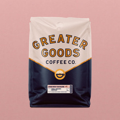 Lunar New Year Blend coffee bag by Greater Goods Coffee Co with a cream top, navy lower half, and a circular logo against a pink background