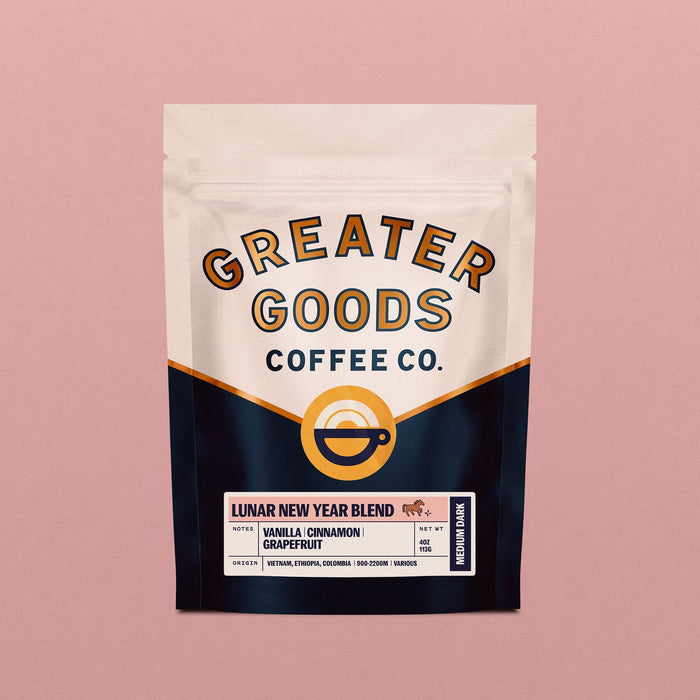 Front view of a Lunar New Year Blend bag from Greater Goods Coffee Co showing beige top panel and bold curved branding with a pink backdrop