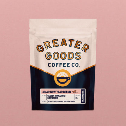 Front view of a Lunar New Year Blend bag from Greater Goods Coffee Co showing beige top panel and bold curved branding with a pink backdrop