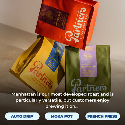 Colorful assortment of Partners coffee bags on a table including Manhattan green bag and red and yellow bags